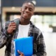 disadvantaged youth grants: happy black student holding binder and carrying backpack