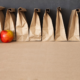 food insecurity: A row of brown bags against a blackboard; one green apple, one red apple in front.