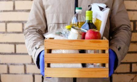 Box with food held by person in jumpsuit, blue gloves