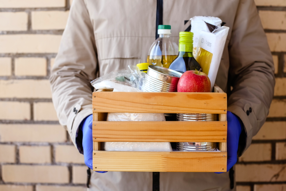  Box with food held by person in jumpsuit, blue gloves