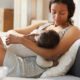 breastfeeding education and access improvement grant; young black mom sitting on sofa bed and breastfeeding baby while holding son in arms