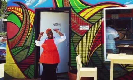 California small business support loans; african american woman chef stands in front of her restaurant cheering