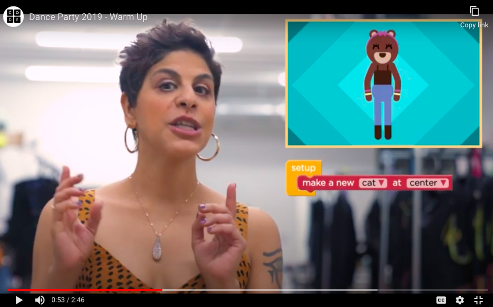 Woman on screen with short dark hair, big hoop earrings gestures, with cartoon character on right.