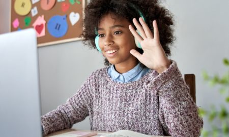 service club: Smiling girl wearing headphones waves and smiles at monitor