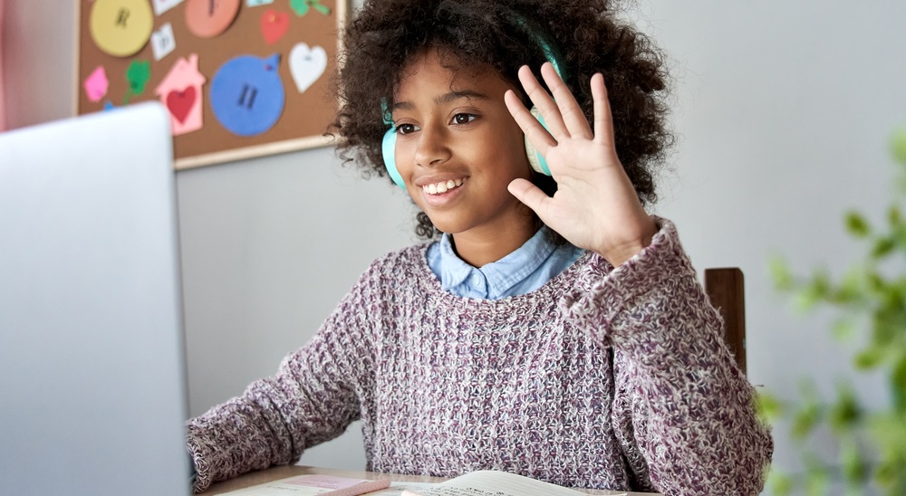 service club: Smiling girl wearing headphones waves and smiles at monitor