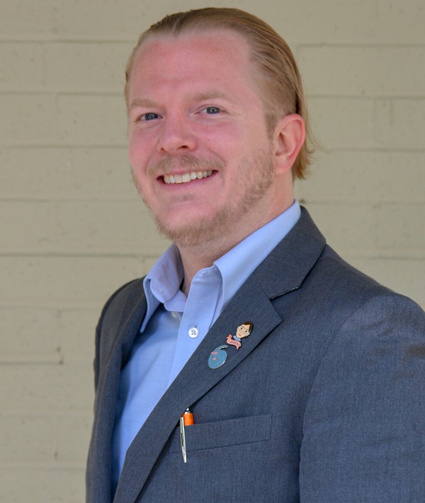 youth voice and leadership: Justin Hensley (headshot), program manager at After-School All-Stars North Texas, man with widow’s peak, reddish beard, mustache, blue suit jacket with 2 lapel pins, light blue button-down shirt