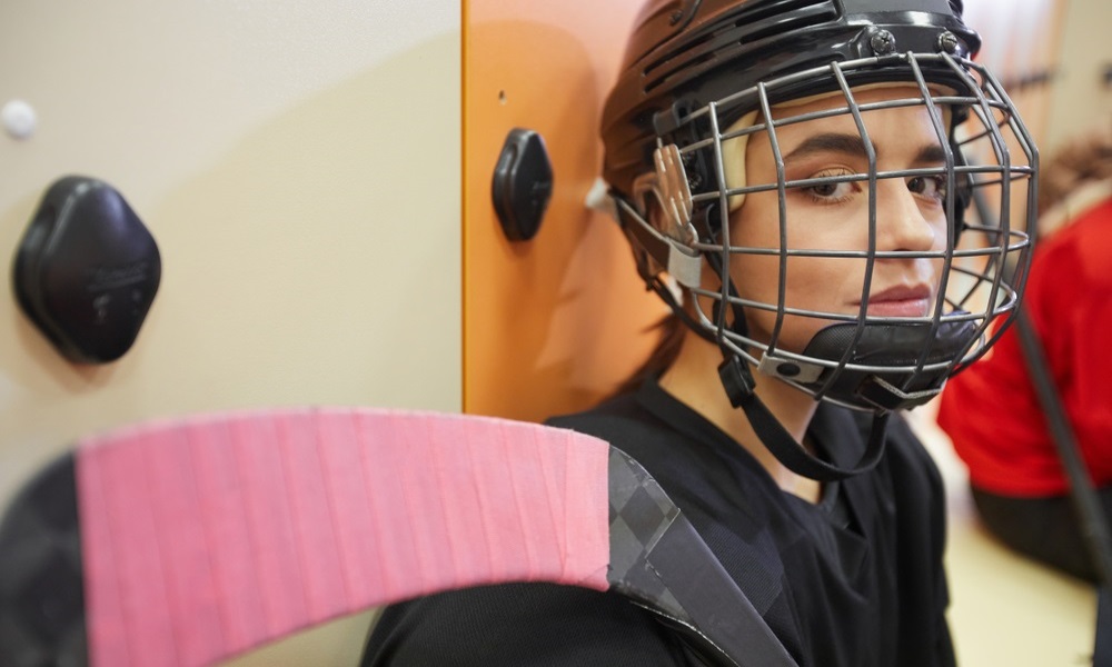 police: Closeup portrait of beautiful young woman wearing hockey gear and looking at camera while posing in locker room