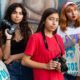 Latinz Arts/Culture support grants; three young Latin female photographers pose for picture in front of painted wall mural