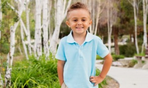 childhood cancer research support grants; young, happy child standing in front of backdrop of trees