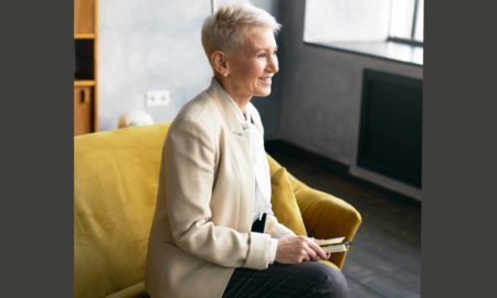 foster youth: High-angle view of elegant middle-aged woman in beige suit sitting in armchair and smiling encouragingly.