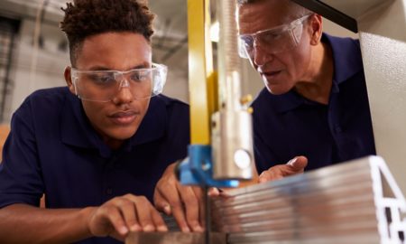 skilled trades, developmental relationships: Carpenter Training Male Apprentice To Use Mechanized Saw