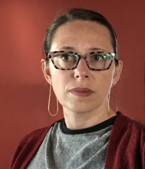 making: Meg Escudé (headshot), educator, artist, woman with brown hair, glasses, gray top, rust sweater