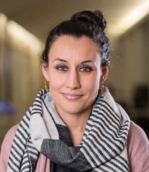 Shirin Vossoughi (headshot), assistant professor of learning sciences at Northwestern University, smiling woman with black bun, earrings, black and white scarf, pink cardigan