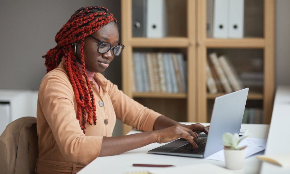  internship: Side view portrait of young African-American woman using laptop 