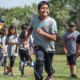 Native youth development, health and wellness grants; young native boy smiling while doing fun physical activity with other native youth