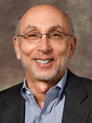 lead poisoning: Dr. Jeffrey L. Goldhagen headshot_smiling balding man with light gray hair, sideburns, beard, glasses, blue shirt, black jacket