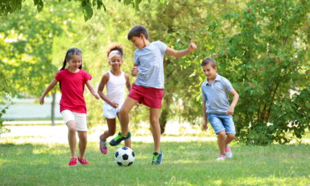 summer learning: 4 kids playing soccer in park