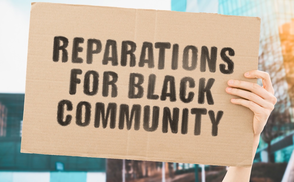 restorative justice: The phrase "Reparations for black community " on a banner in men's hand with blurred background.