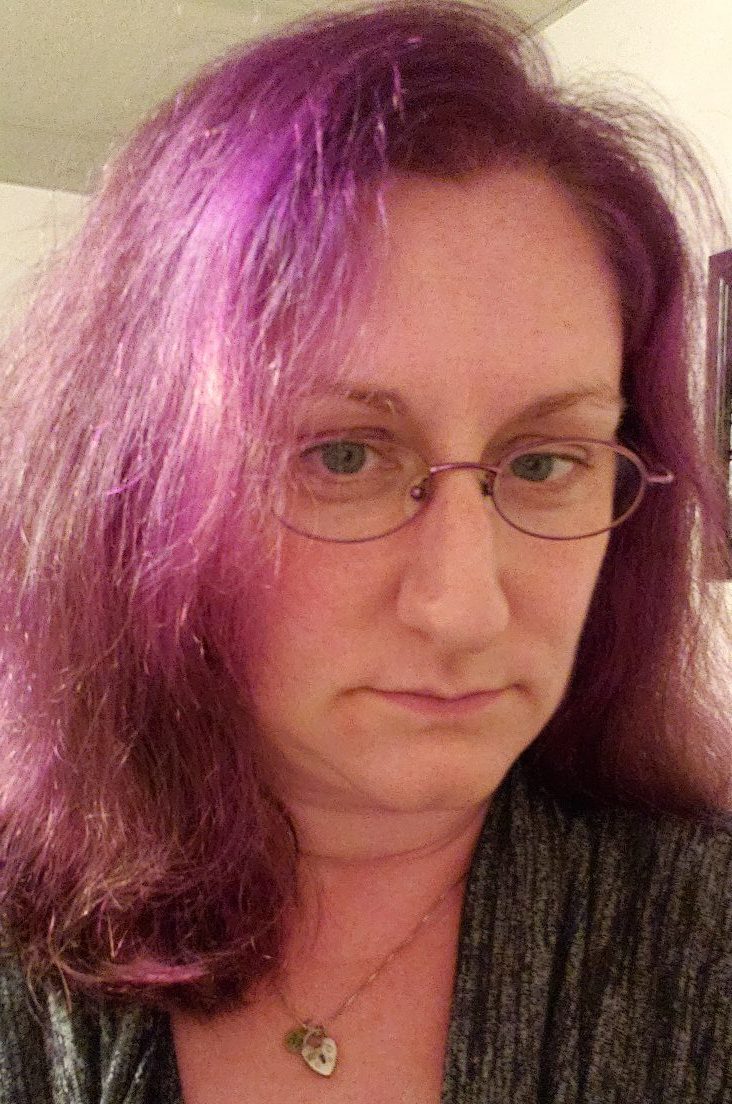 autism: Woman with long red hair with purple highlights, necklace, glasses, green top
