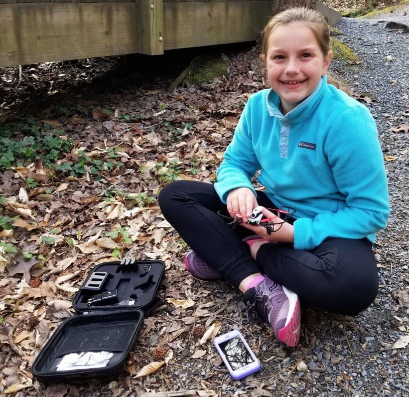 Georgia girls' STEM program; young girl sitting on ground with phone and tech kit