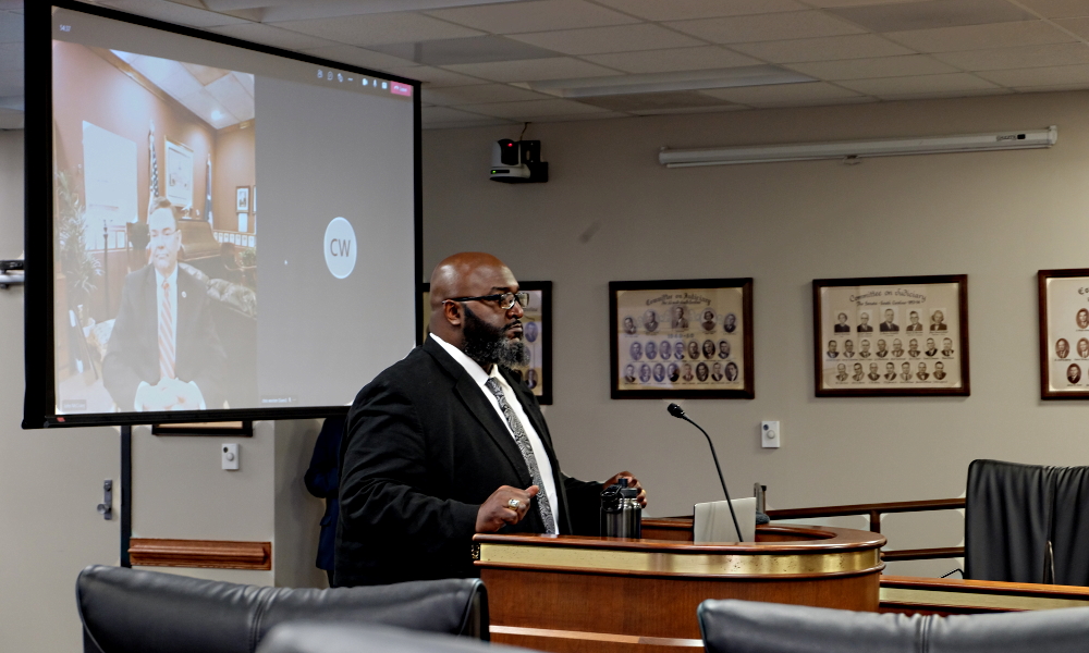 Man in dark suit and white shirt sits behing witness stand South Carolina Department of Juvenile Justice Director Freddie Pough testifies in front of state lawmakers in Columbia, S.C.