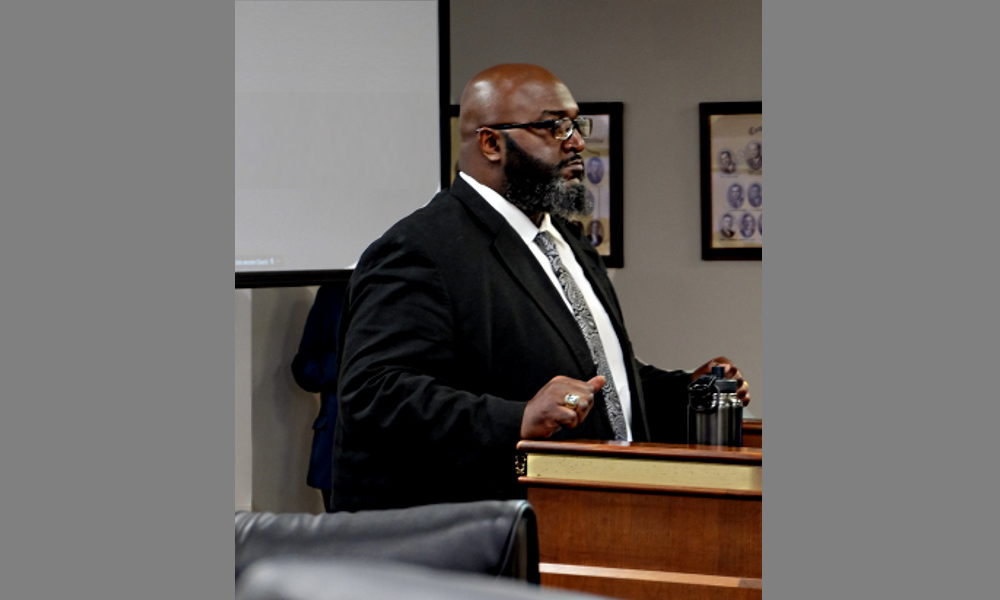 Man in dark suit and white shirt sits behing witness stand South Carolina Department of Juvenile Justice Director Freddie Pough testifies in front of state lawmakers in Columbia, S.C.