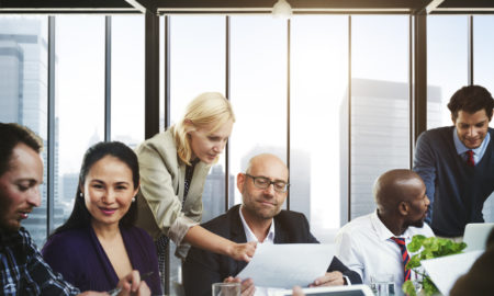 Post-Pandemic Nonprofit: Group of 6 people in active discussion sit & stand around conference table