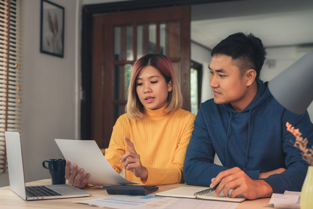 foster youth tax credit: Young Asian couple sit at table reviewing paperwork