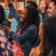youth-centered arts, culture, and social change grants: young woman raising her hand in meeting while smiling