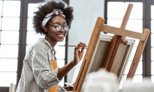 arts culture organization support grants: young black female artist working on painting