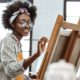 arts organization support grants: young black female artist working on painting