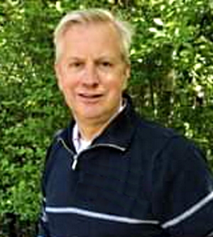 Therapeutic foster care: Director Tom Rawlings headshot of blonde man in nay polo shirt in front of outdoor greenery