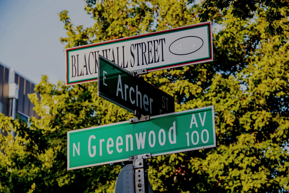 Tulsa OST entrepreneurship camp: Three street signs closeup in front of green treetops.