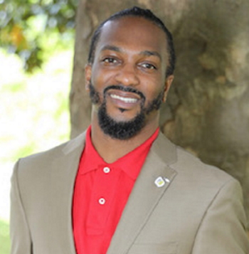 learning disabled protections: Jasoon B. Allen headshot smiling black man with short dark hair and beard in tan suit with red shirt in front of tree trunk and greenery