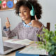learning disabled protections: Young black girl with long natural hair and turquoise headsphones wearing gray sweater both hands in thumbs up sign sits at desk with laptop and green plant