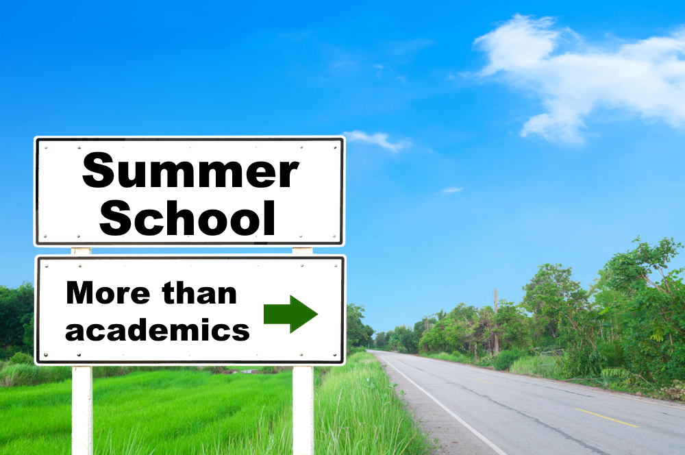 Summer school: empty road surrouned by green files and tress with wite roadsign"Summer school more than academics"