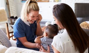 rural maternity care, healthcare grants: female doctor putting stethoscope on baby held by mother