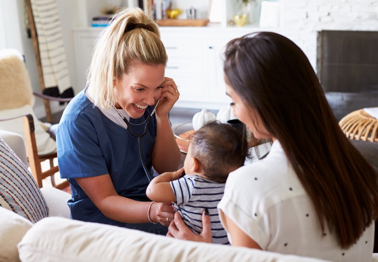 rural healthcare grants: female doctor putting stethoscope on baby held by mother