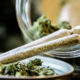NY marijuana laws: Two hand-rolled marijuana joints rest on lid and glass jar lying on its side with marijuana buds in it
