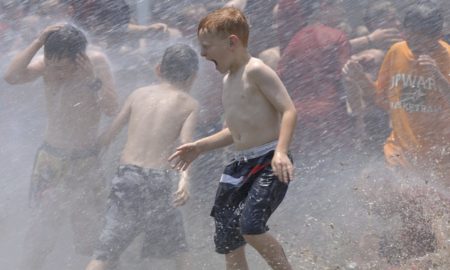 Summer camps hit with COVID outbreaks, are schools next?: picture of children playing in water on hot day