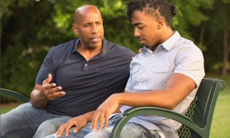 minority community mental health: man mentors young african american man on park bench
