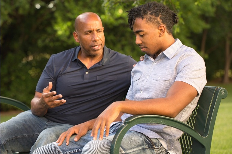 minority community mental health: man mentors young african american man on park bench