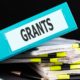 seeking grants with limited time and resources: graphic of stack of paper and binder with word "grants"