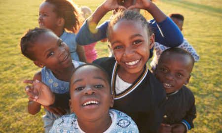 Build Back Better: Group of 6 young Blackchildren smilimh lookng up at camera