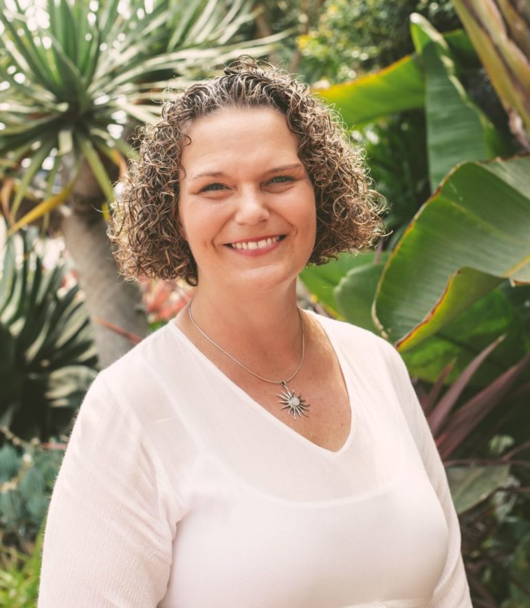 Nonprofit Toolbox: Headshot woman with curly blonde hair and sun medallion necklace in pale pink top