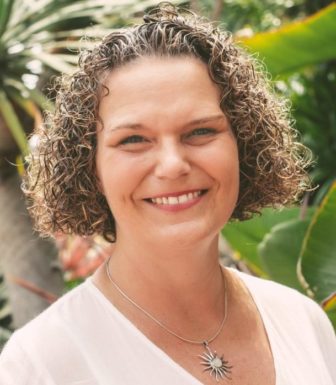 Nonprofit Toolbox: Headshot woman with curly blonde hair and sun medallion necklace in pale pink top