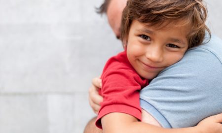 New England child health research grants: young, smiling boy being hugged