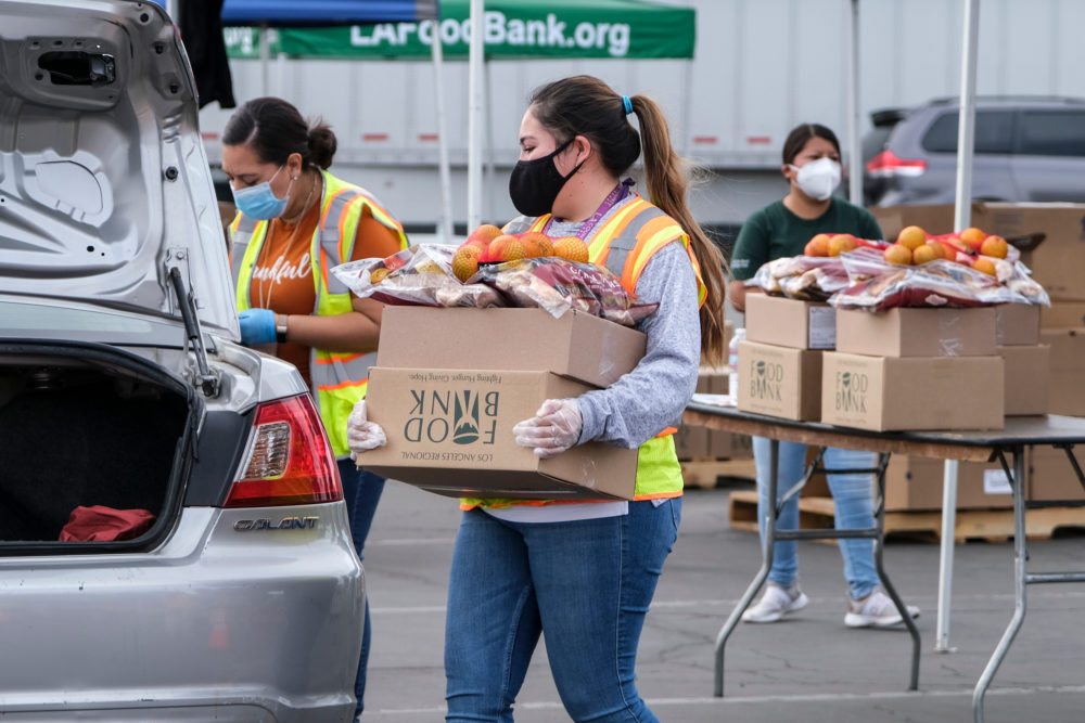 NP Toolbox Donor communications: Three women in masks wearing work clothes load carboard boxes filled with food donations into vehicles