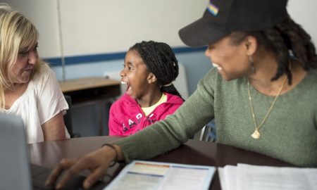 Increasing family engagement in student learning grants: young black girl and her mom happily speaking with educator