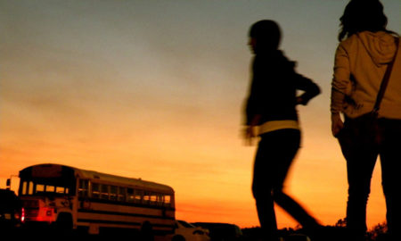 Electroshock therapy: Two children in walking to school bus are silhouetted against an early morning sunrise sky